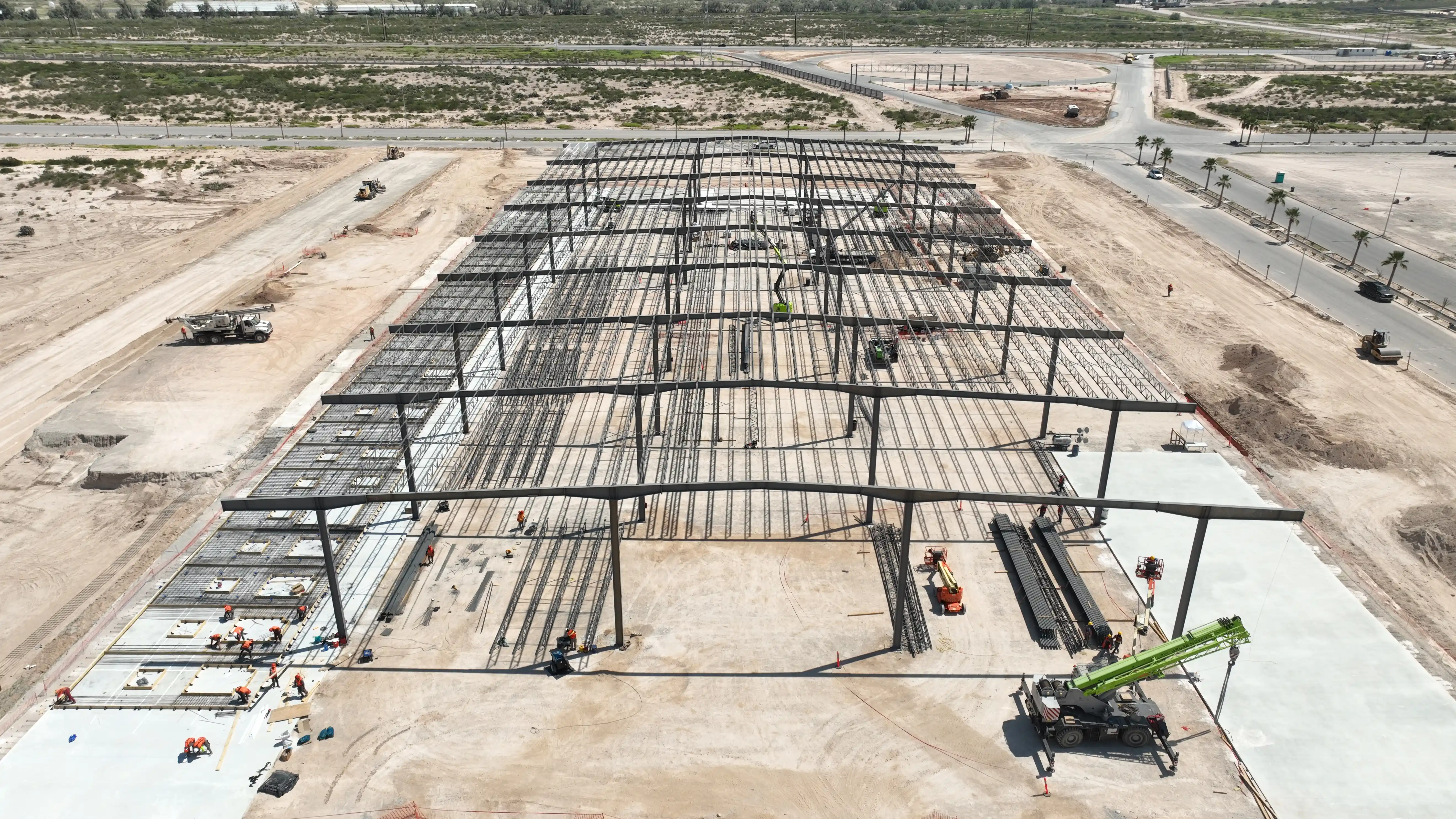 Vista aérea del montaje de una estructura metálica industrial masiva, reflejando el compromiso con la calidad en la construcción y el cumplimiento de la certificación ISO 9001.