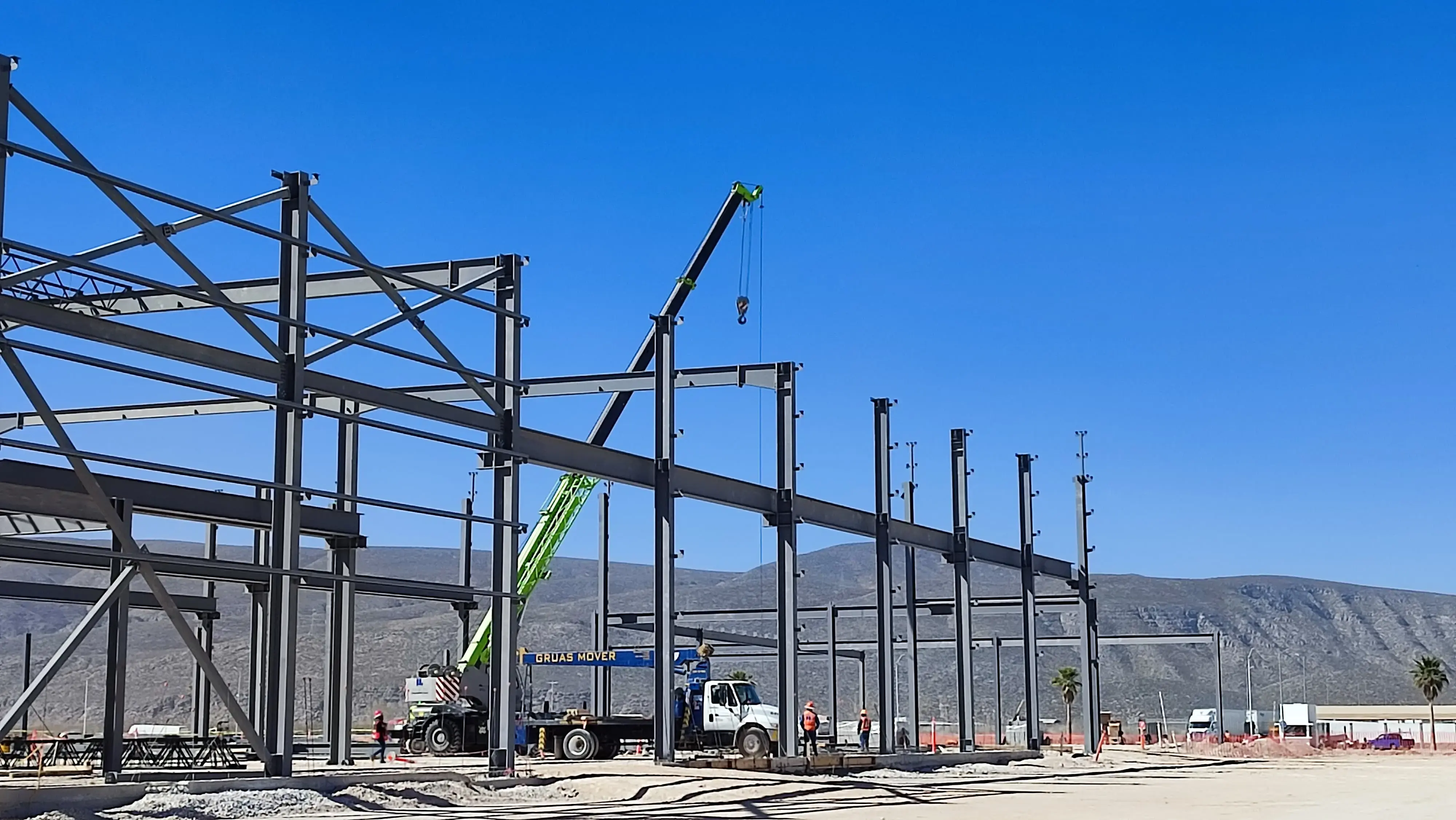 Fotografía de una obra de construcción de una nave industrial con estructura de acero y grúas operando, ilustrando la actividad del sector de la construcción impulsado por el T-MEC en construcción